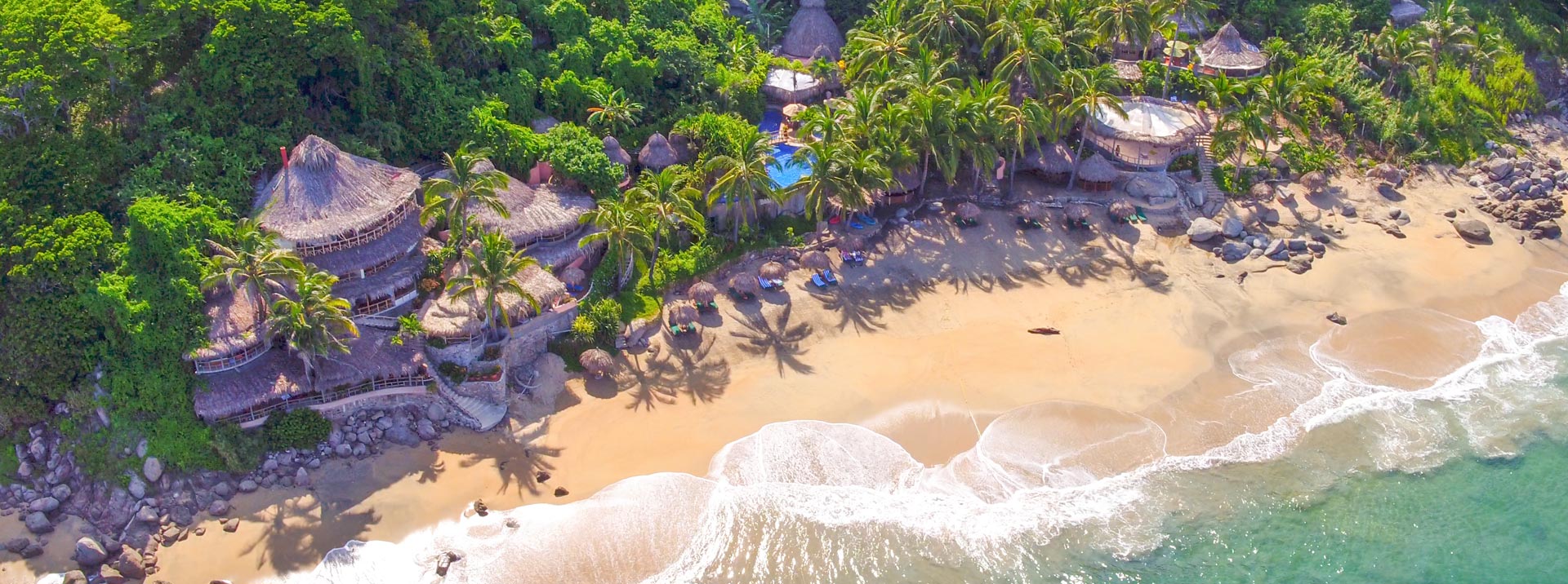 Playa Escondida from the air: palapa roofs in the jungle above a private beach